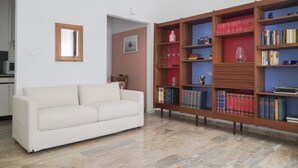 A living room with a white sofa, a wooden bookshelf, and a small table with a vase. - Apartment in the center of Venice (Venezia)