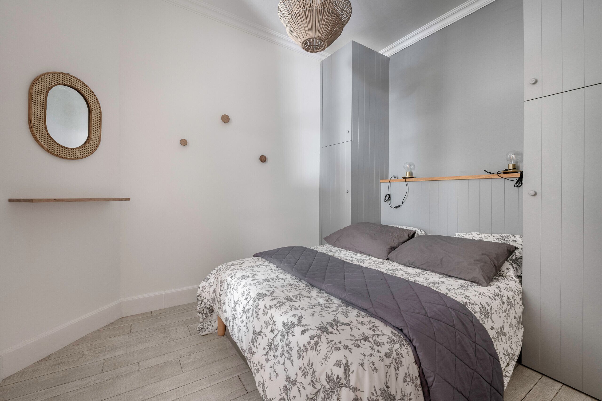 Une chambre à coucher avec un lit, un miroir, une étagère et un luminaire suspendu.