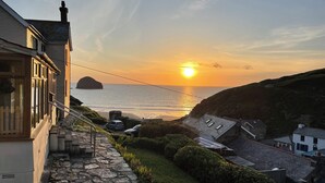 Une propriété située sur la côte, avec un chemin de pierre menant à une zone herbeuse, offrant une vue sur la mer et une petite île.