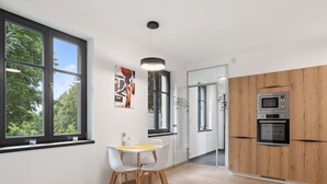 A modern kitchen with a wooden cabinet, a built-in oven, and a dining area with a table and chairs. - Beautiful apartment for 3 guests with WIFI, TV and terrace (Železný Brod)