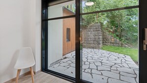 A modern interior with a large sliding glass door leading to an outdoor stone patio and a wooden structure. - Beautiful apartment for 3 guests with WIFI, TV and terrace (Železný Brod)