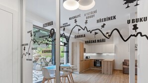 A modern interior with a dining area, kitchen, and a glass wall with a mountain trail map. - Lovely apartment for 4 people with WIFI, TV and terrace (Železný Brod)
