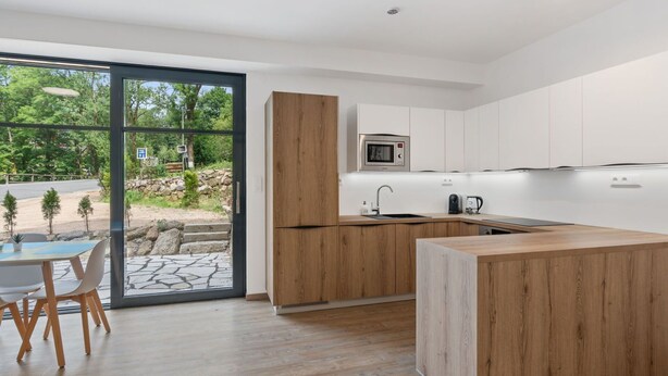 A modern kitchen with a wooden island, white cabinets, and a built-in microwave. - Lovely apartment for 4 people with WIFI, TV and terrace (Železný Brod)
