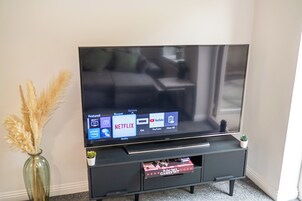 A flat-screen TV on a black stand with a Netflix interface displayed.