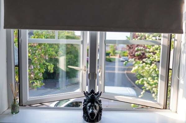 A window with a view of greenery and parked cars outside. - House Sleeps6-garden-petsok-parking-long Stay Disc (Nottingham)