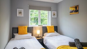 Een slaapkamer met twee bedden, een raam, een lamp en een schilderij.