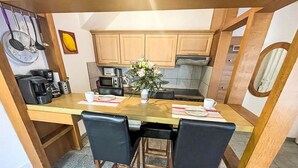 Una cucina compatta con mobili in legno, un tavolo da pranzo con sedie e una macchina da caffè.