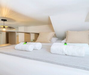 Quarto de hotel com uma cama grande, duas almofadas, uma mesa de cabeceira e um abajur.