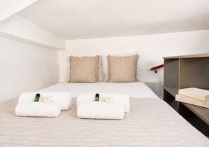 A bedroom with a bed, two pillows, a bedside table, and a shelf. - 1571 Lombards (Paris)