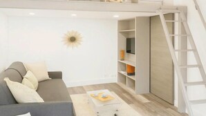 Una sala de estar moderna con un sofá gris, una mesa de centro, una estantería y una escalera.