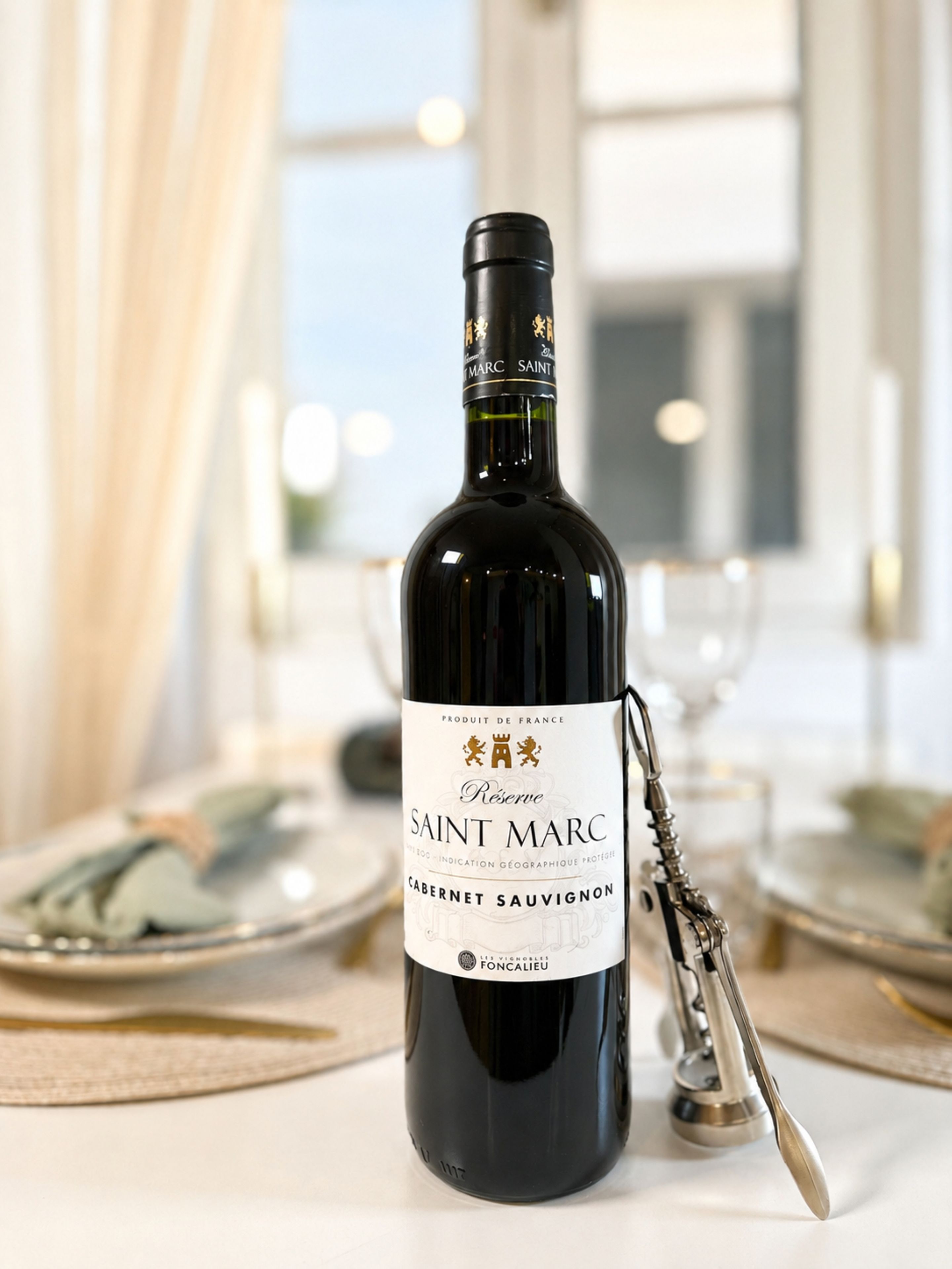 A bottle of Saint Marc Cabernet Sauvignon wine with a corkscrew beside it, placed on a table with a placemat.