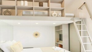 Un dormitorio con cama, mesita de noche, lámpara, estante con objetos y una escalera.