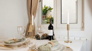 Una mesa de comedor dispuesta con platos, vasos, cubiertos, una vela y una botella de vino.
