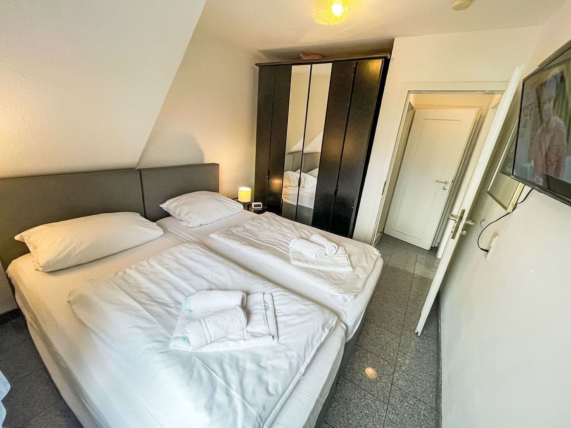 A hotel room with a bed, a wardrobe, and a television.