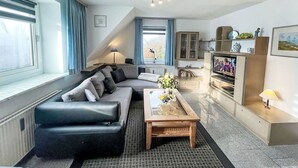 A modern living room with a sectional sofa, a coffee table, a TV, and a cabinet with decorative items.