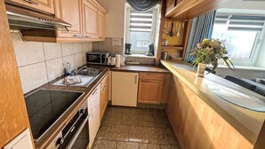 A compact kitchen with a microwave, toaster, sink, and a small window with curtains.