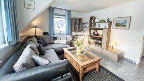 A modern living room with a sectional sofa, a wooden coffee table, and a flat-screen TV mounted on a cabinet.