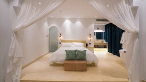 Una camera da letto con un letto grande, una panca e un bagno sullo sfondo.