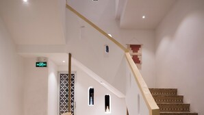 Un interno moderno con una scala, una tappeto decorato e un motivo geometrico sul muro.