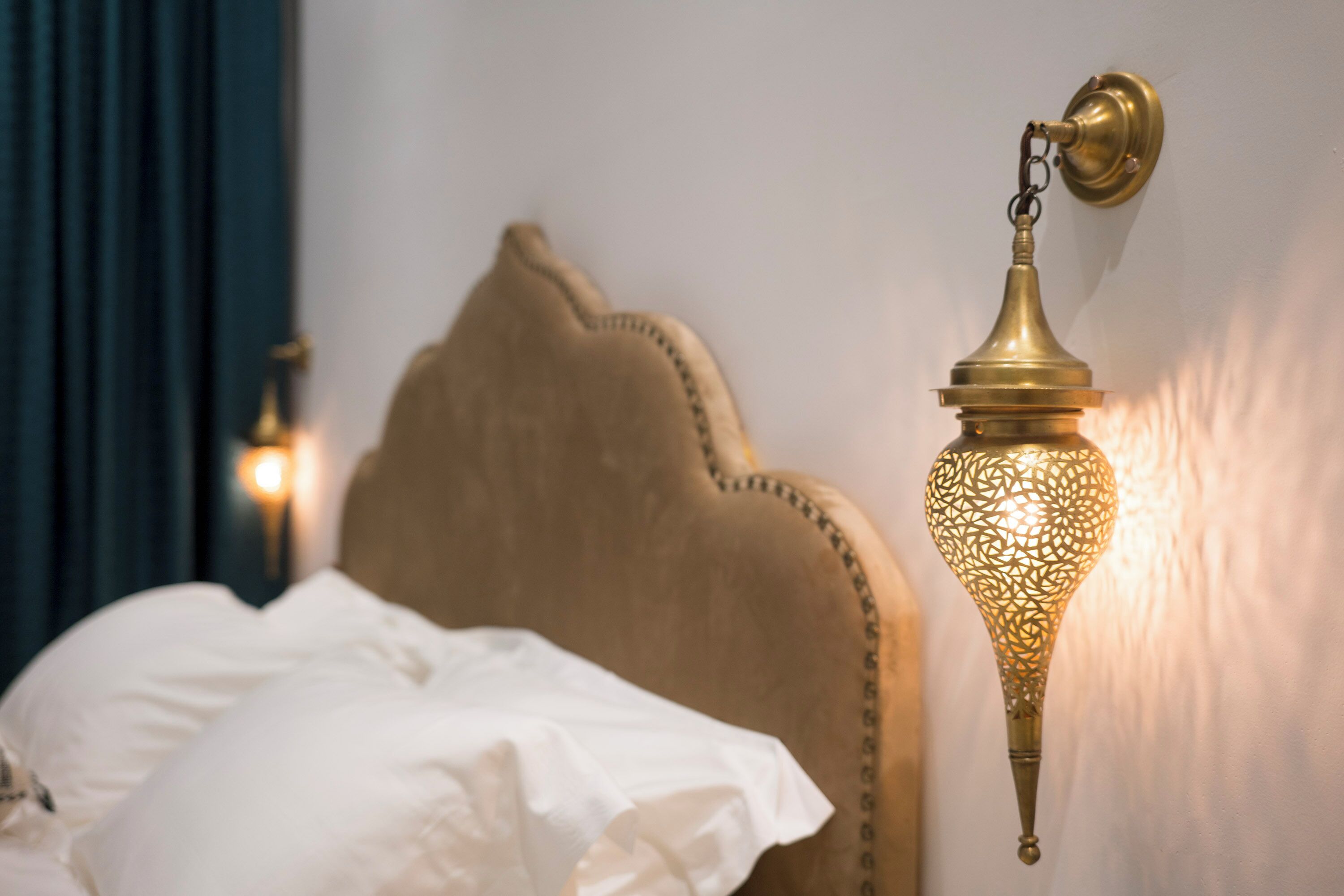 A bed with a headboard and a wall-mounted lamp.