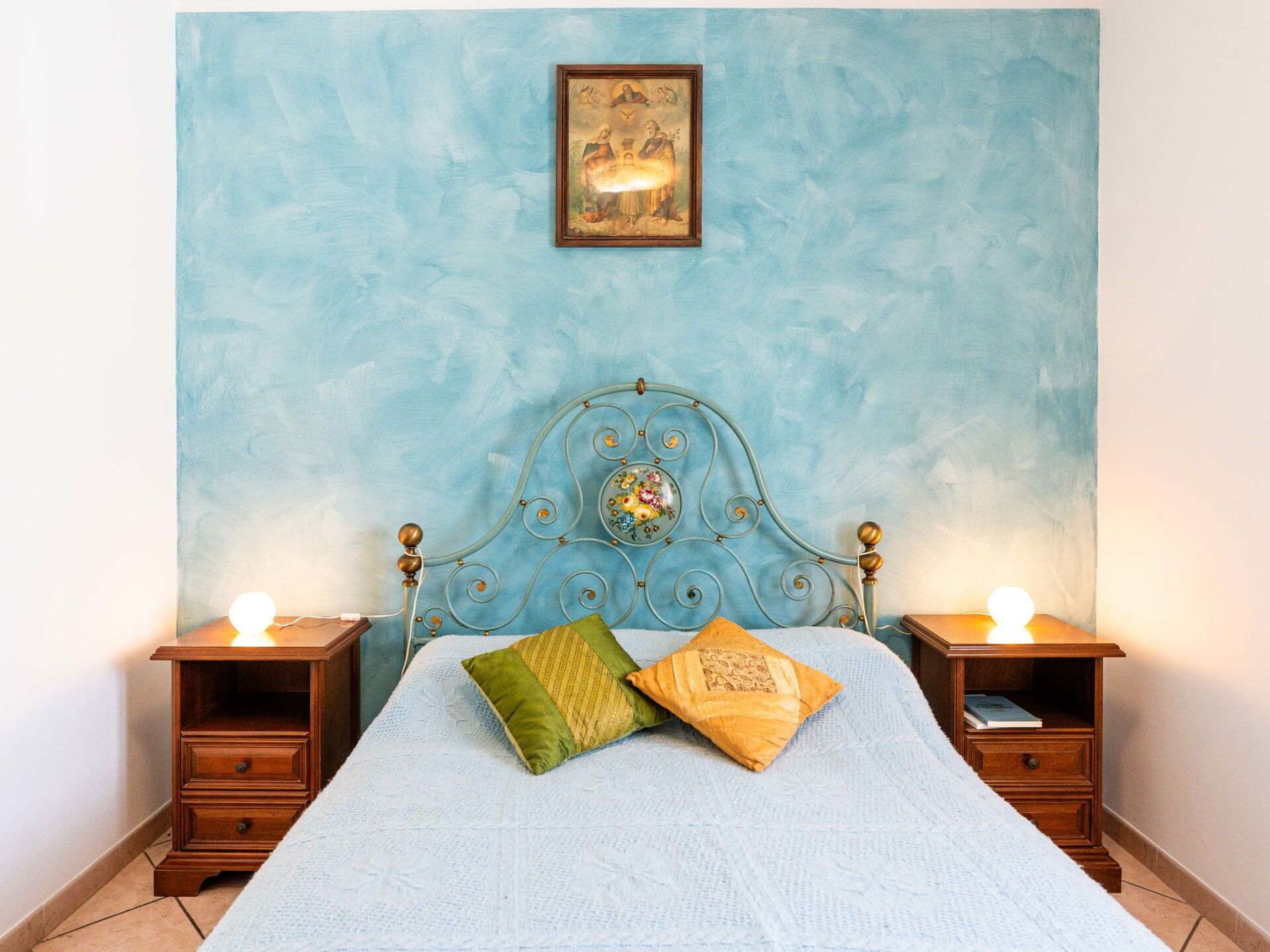 Ein Schlafzimmer mit einem Bett, zwei Nachttischen, einem Wandbild und einem Schrank.