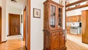 Un pasillo con un armario de madera, una puerta y una zona de cocina con armarios y electrodomésticos.