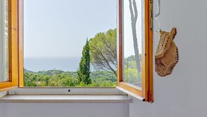 A window with a view of a coastal landscape, a wooden door, and a crocheted bag hanging on the door. - Beautiful  villa for 6 people with A/C, WIFI, terrace and pets allowed (Castiglione Della Pescaia)