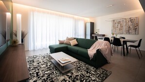 Een moderne woonkamer met een groene bank, een salontafel en een eetgedeelte met stoelen en een tafel.