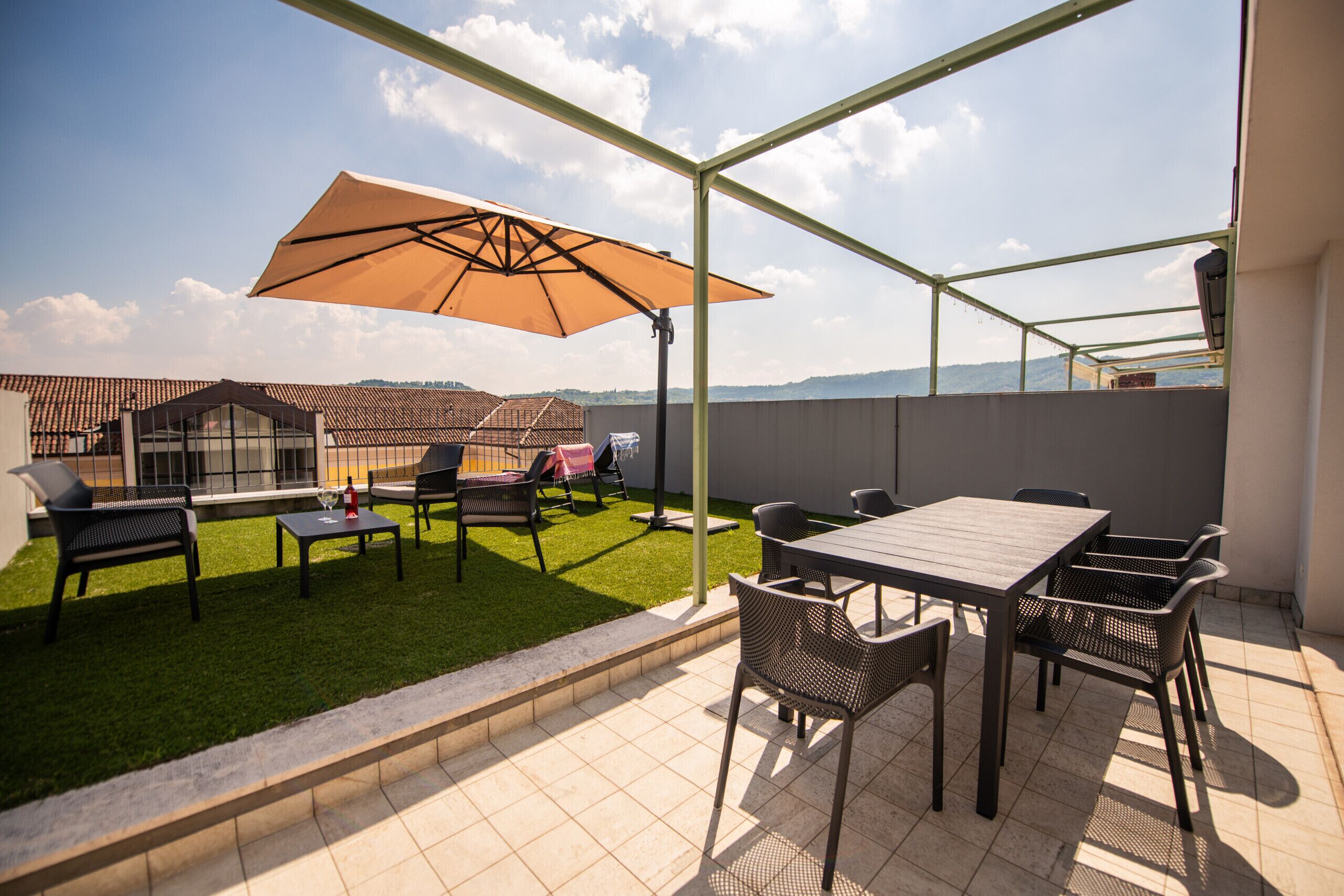 An outdoor patio with a table and chairs, a large umbrella, and a view of a building in the background.