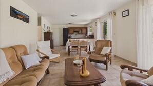 Un salón amplio con sofá, sillones, una mesa de centro y un comedor con mesa y sillas.