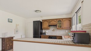 Una cocina con armarios de madera, un refrigerador negro, salpicadero de azulejos y un ventanal con vistas.