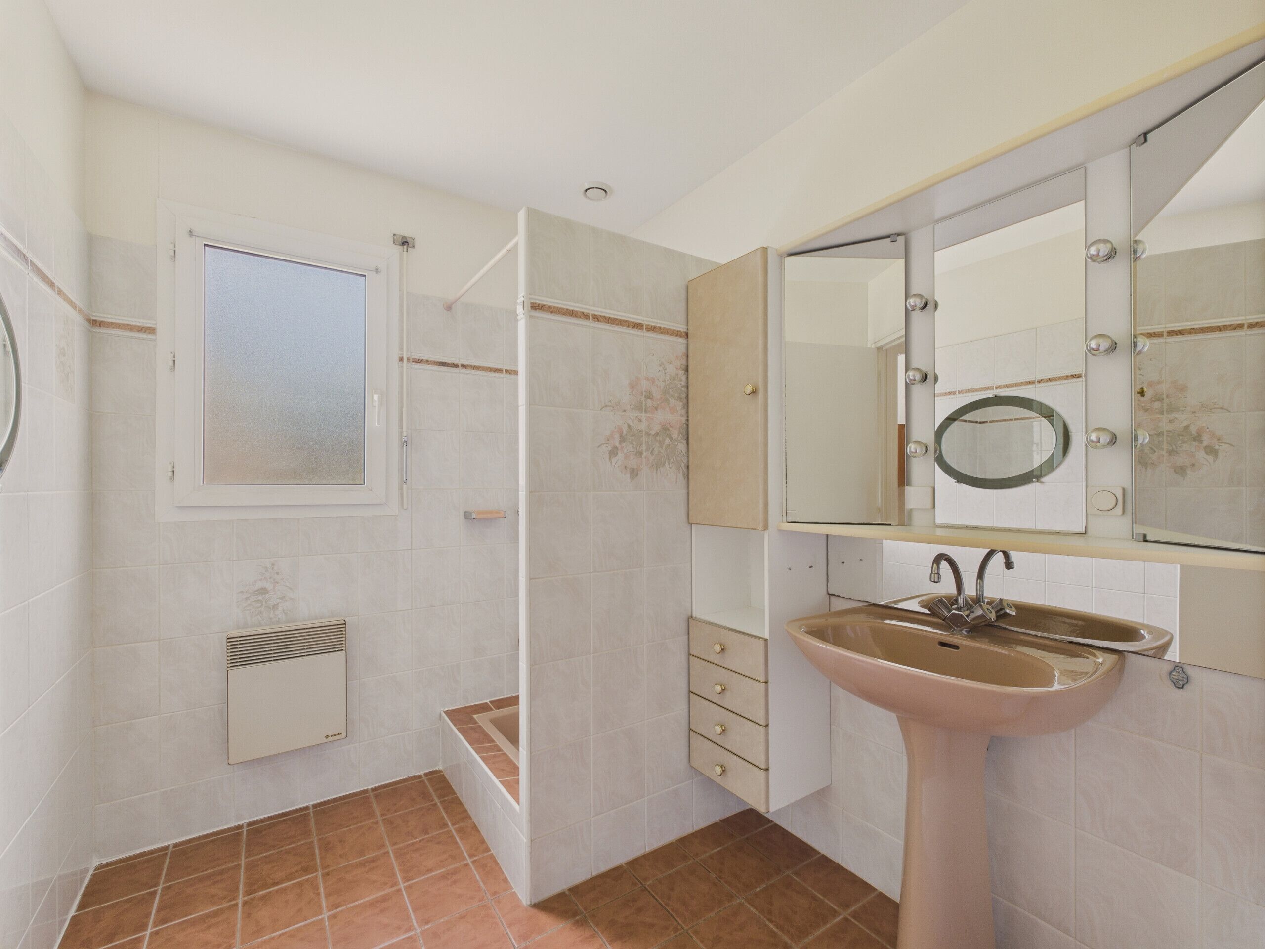 Une salle de bain avec une douche, un lavabo, un miroir et une fenêtre.