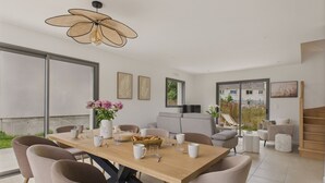 A modern dining area with a wooden table, cushioned chairs, and a ceiling fan. - Lovely family home for 8 with garden (Erquy)