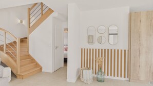 A modern interior with a wooden staircase, a wall-mounted mirror, and a striped panel design. - Lovely family home for 8 with garden (Erquy)