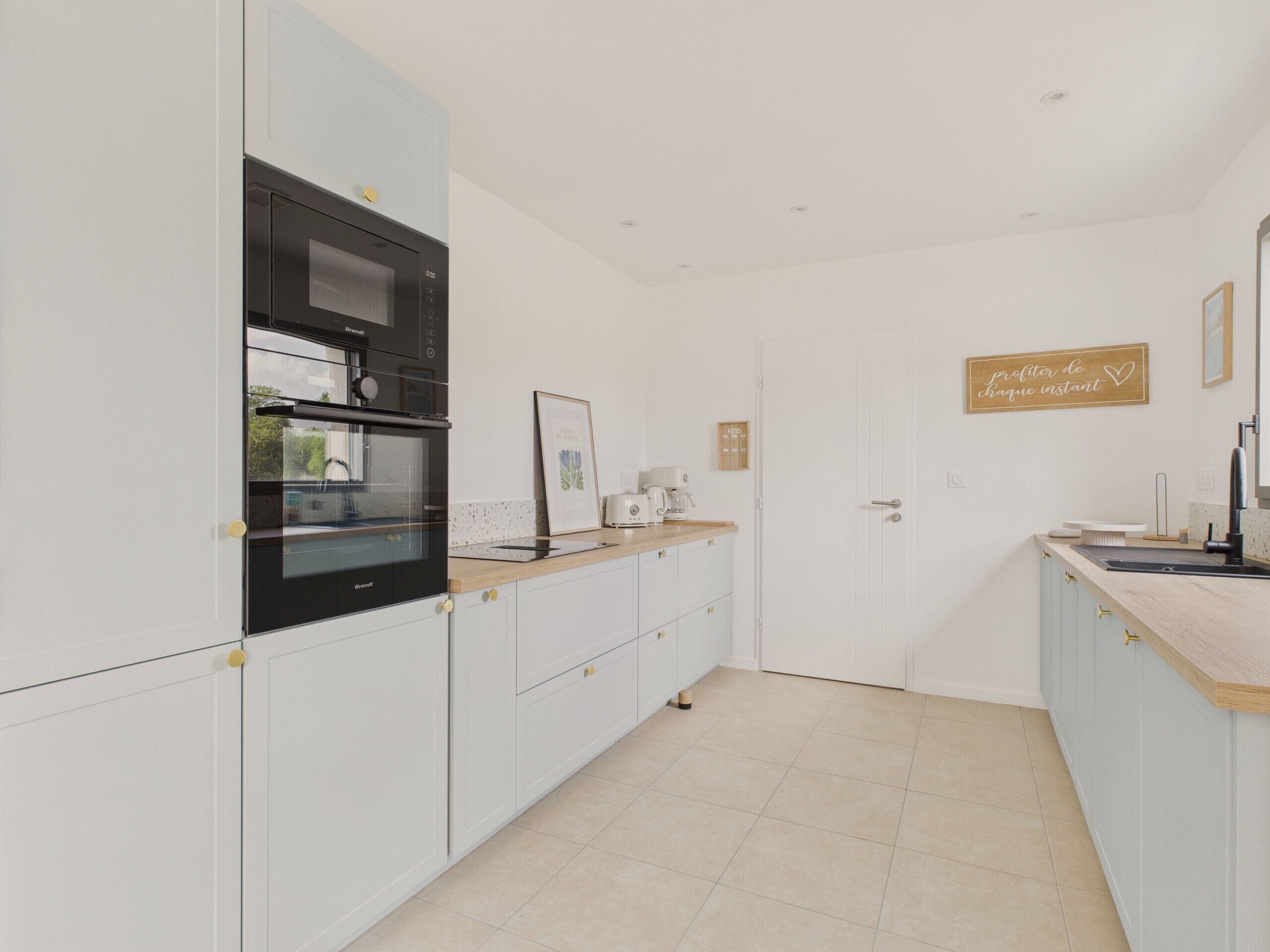 Una cocina moderna con muebles blancos, un horno negro y una encimera de madera.