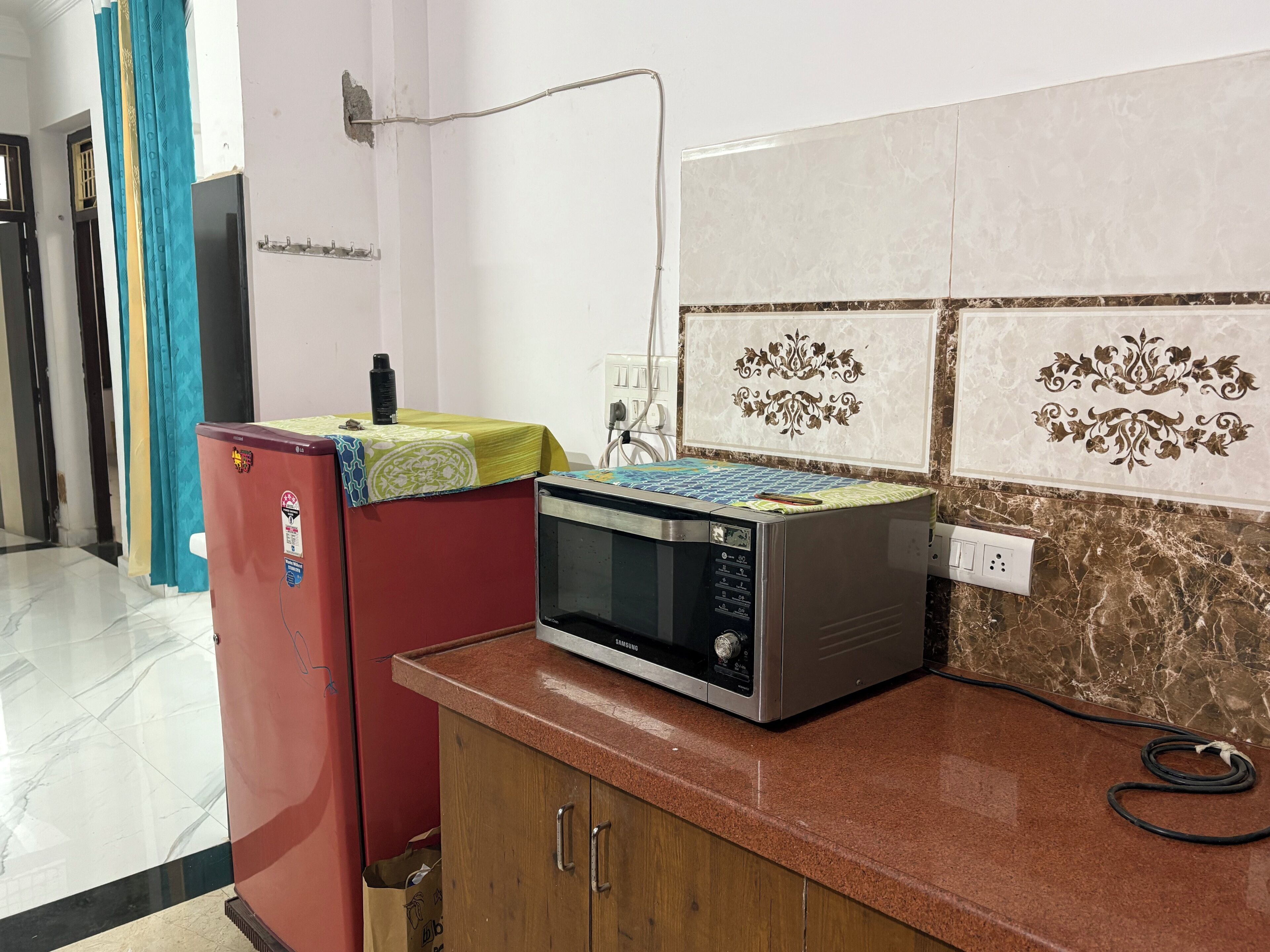 Una cocina con microondas, un refrigerador rojo y un armario.
