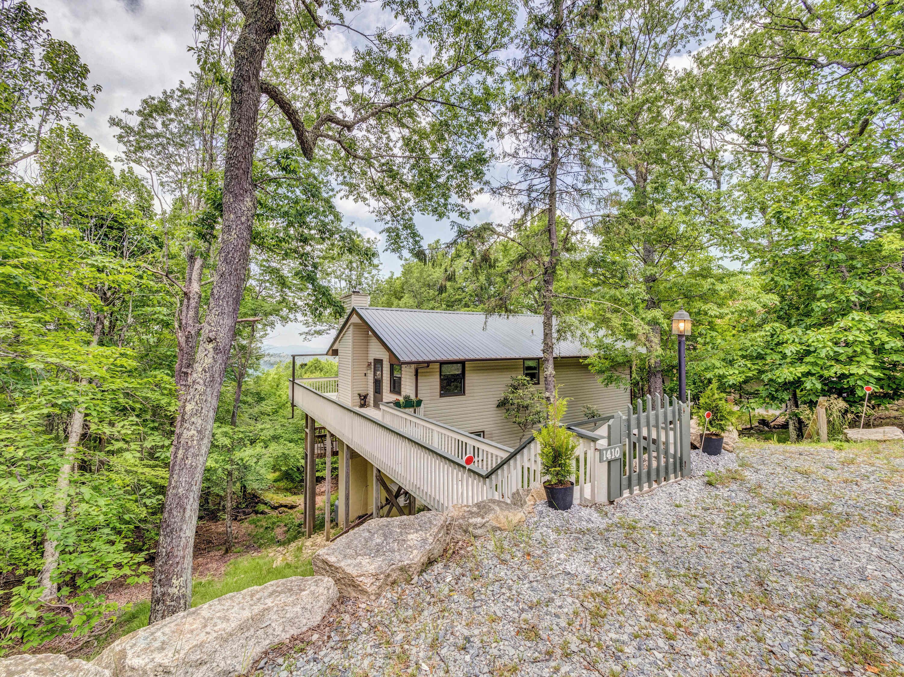 A cabin with a deck, surrounded by trees and a rocky landscape.