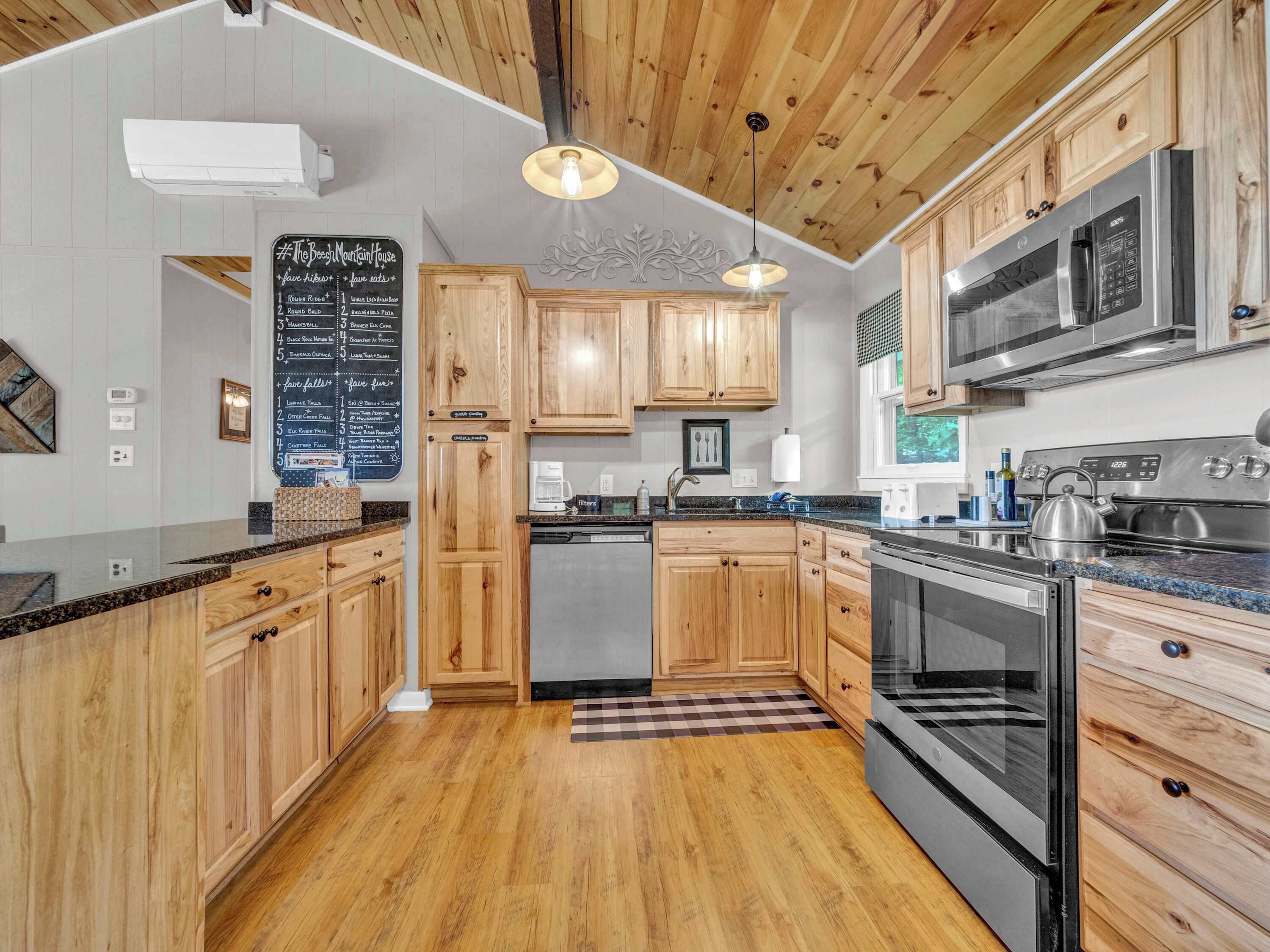 Una cocina moderna con armarios de madera, electrodomésticos de acero inoxidable y un menú en una pizarra.