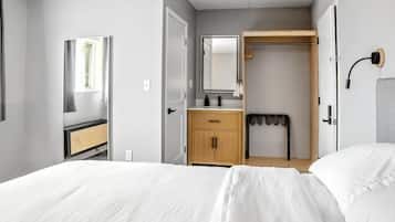 A bedroom with a bed, a wooden wardrobe, a mirror, and a shower area.