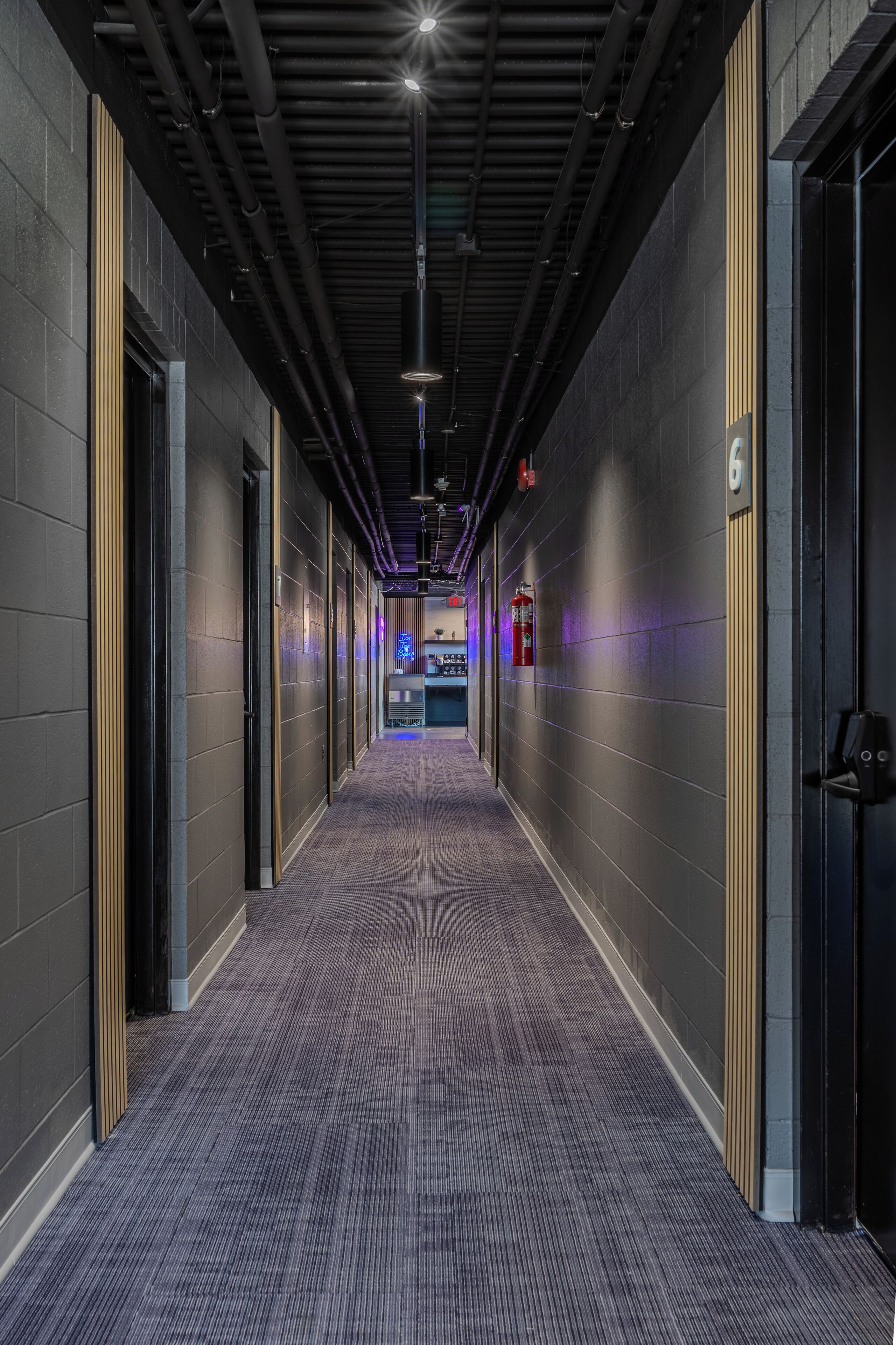 A hallway with a dark floor, walls with a number '6' sign, and a fire extinguisher mounted on the wall.