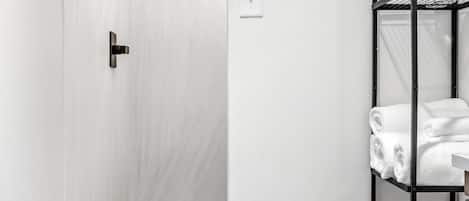 A bathroom with a white door, a black towel rack with towels, and a patterned floor.