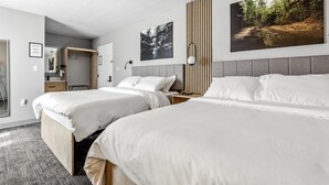 Una habitació d'hotel amb dos llits, un mirall gran, un armari i obres d'art a les parets.