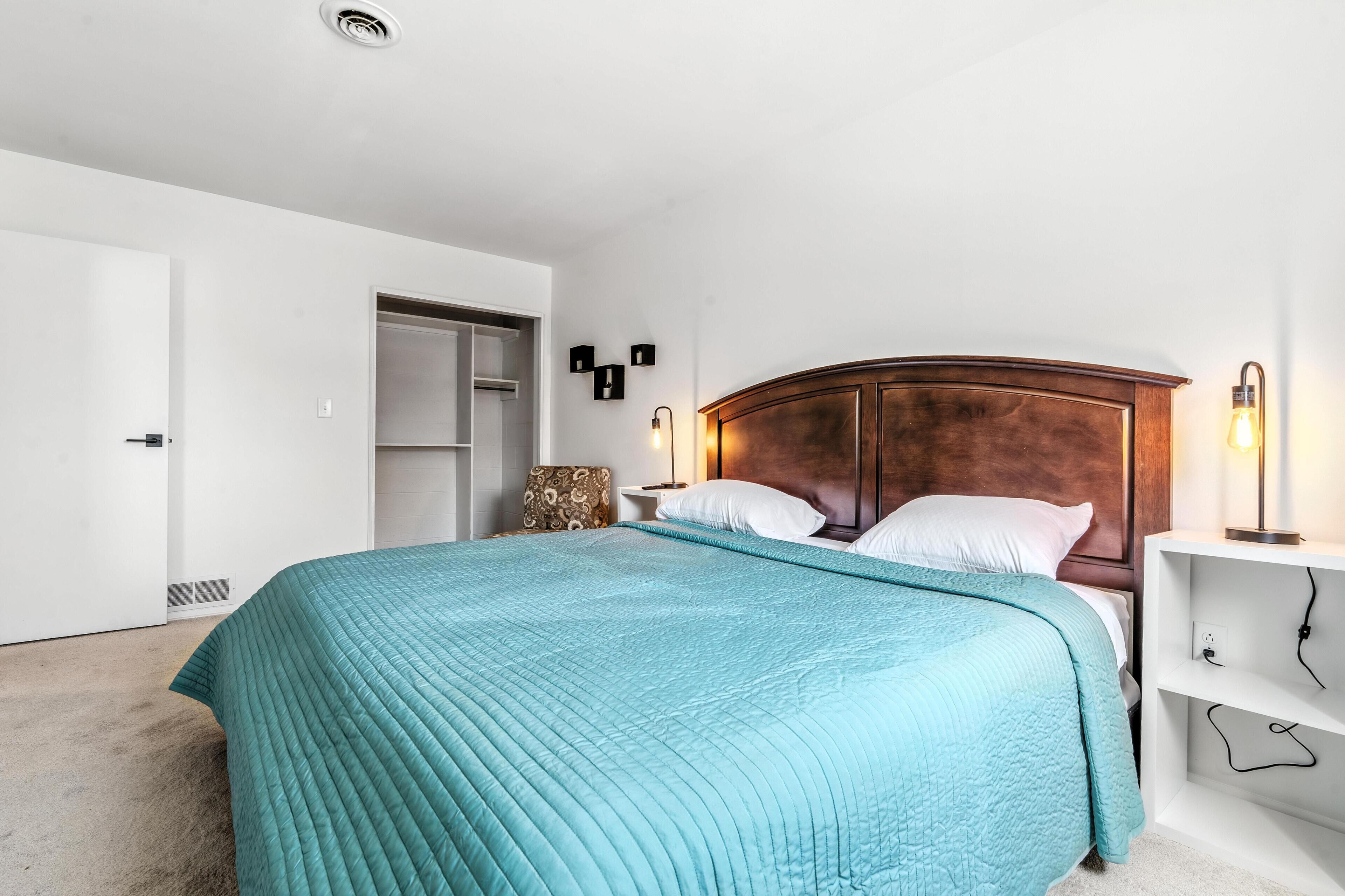 A bedroom with a bed, a nightstand, a wall-mounted lamp, and a wardrobe.