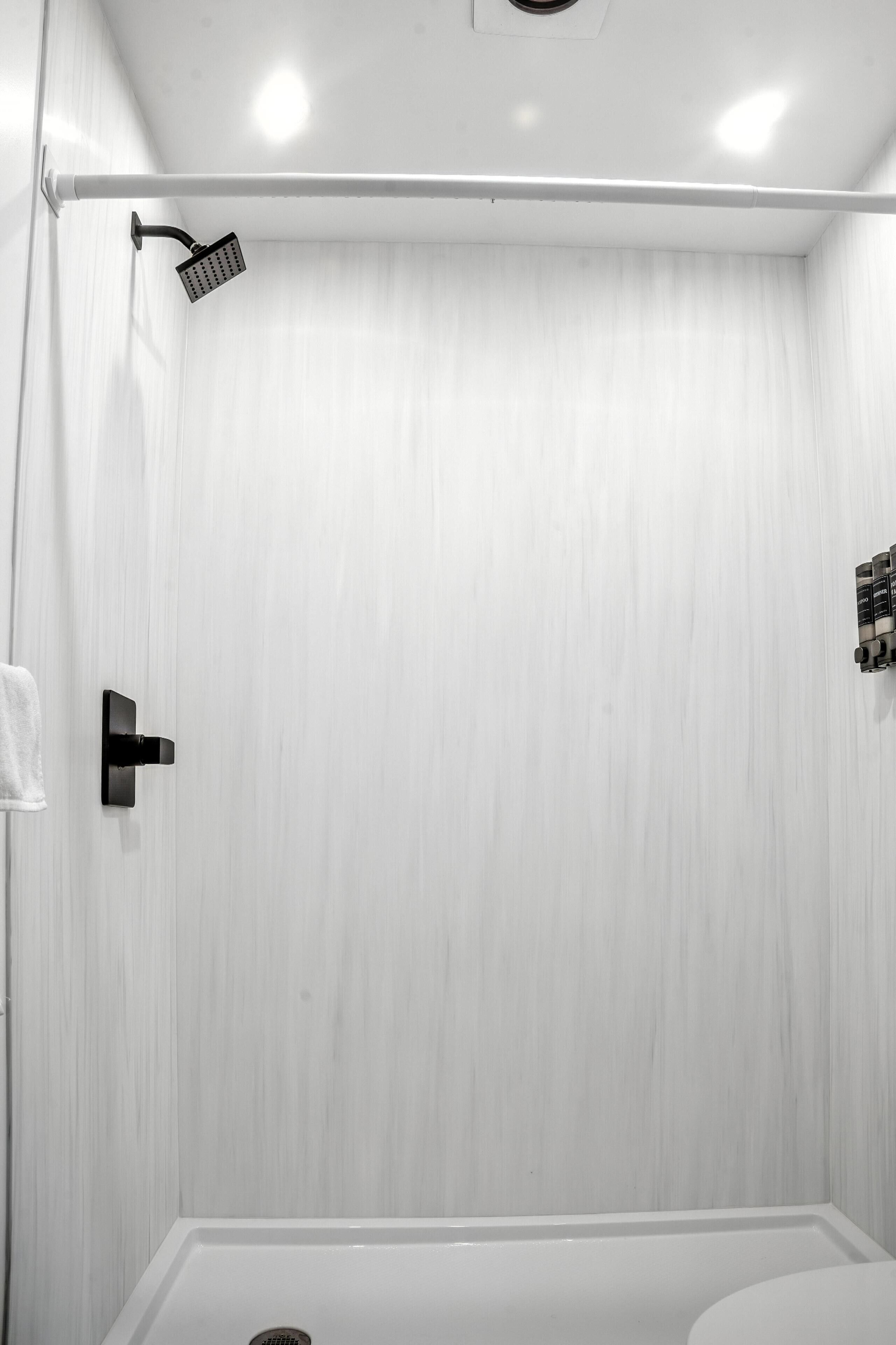A modern bathroom with a shower, toilet, and a towel rack.