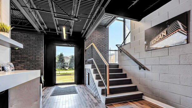 Un interior modern amb una escala, una taquilla d'hostaleria i una vista a través d'una porta de vidre.