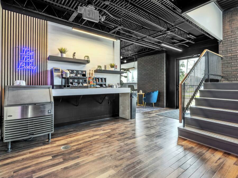 Un área de cocina moderna con un letrero de neón, cafeteras y una escalera.