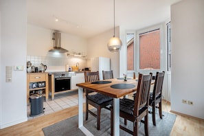 A compact kitchen with a dining area, a built-in oven, and a large window.