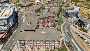 Un hotel de varios pisos con un patio central, estacionamiento y vistas del paisaje circundante.