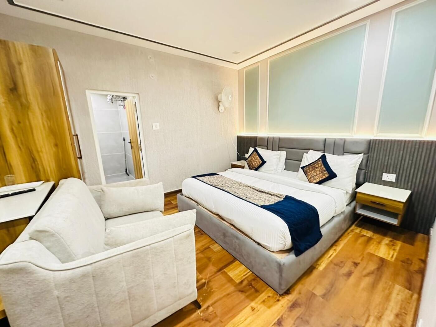 Une chambre d’hôtel moderne avec un grand lit, un canapé, une table de chevet et un miroir.