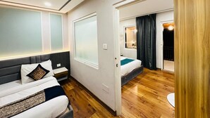 A hotel room with two beds, a large window, a door leading to a balcony, and a wooden floor. - Excel Hotels & Resorts Mall Road Nainital (Nainital)